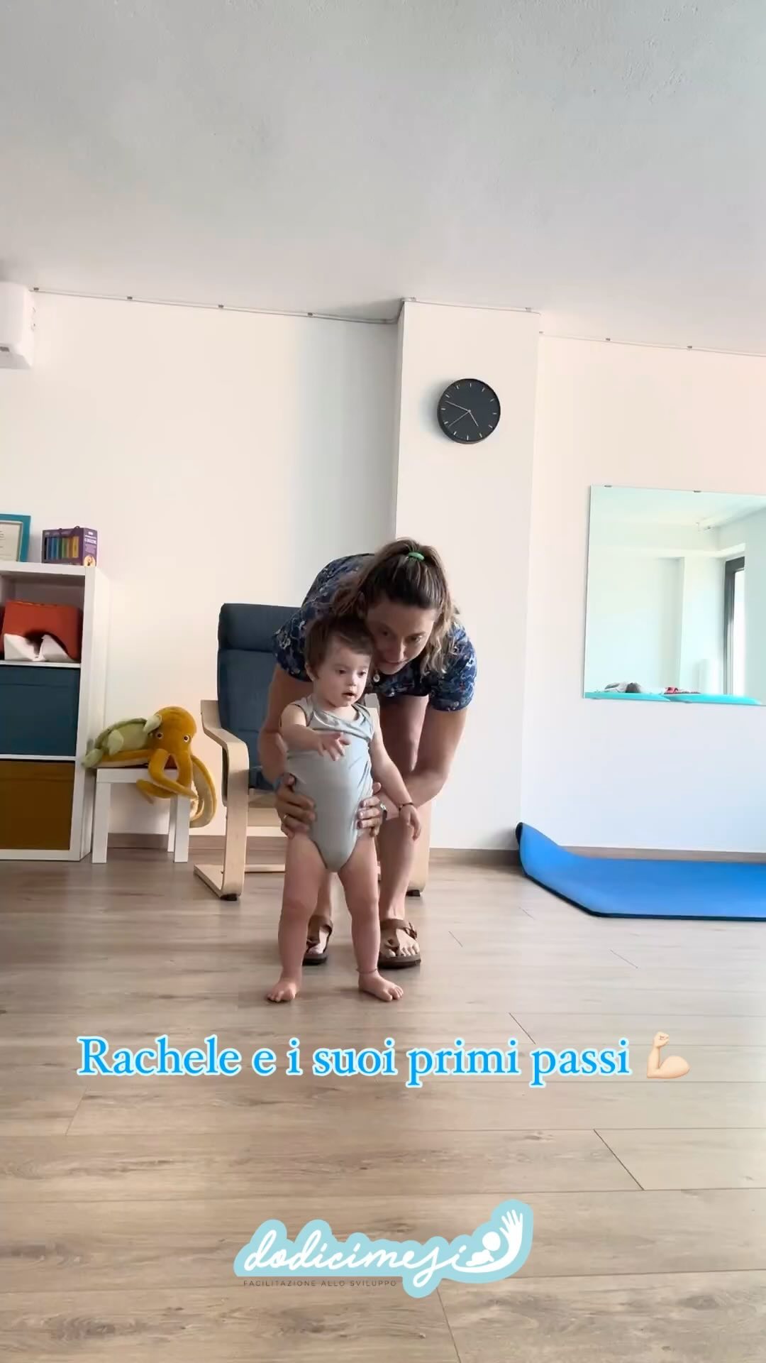 Un genitore tiene in braccio un neonato mentre parla con un’osteopata pediatrica in uno studio luminoso.